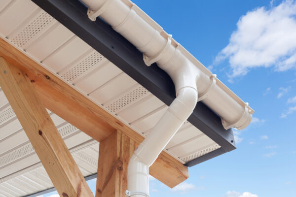 SIP panel house construction. New white rain gutter.  Drainage System with Plastic Siding Soffits and Eaves against blue sky